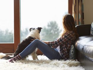 Woman and dog sitting on a furry rug