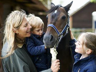 Mature woman with son and daughter petting horse